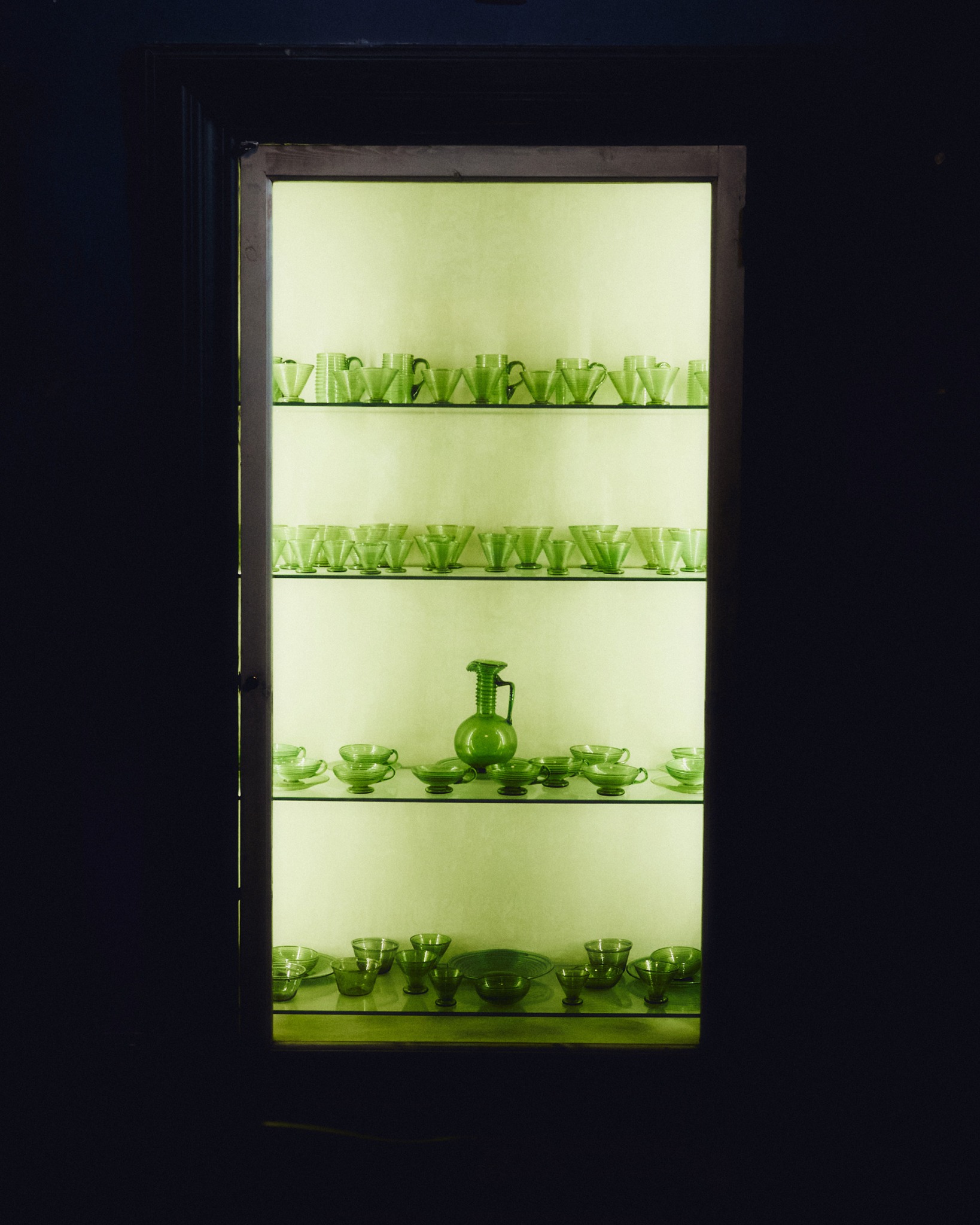 Illuminated shelves of green glassware in Nicosia