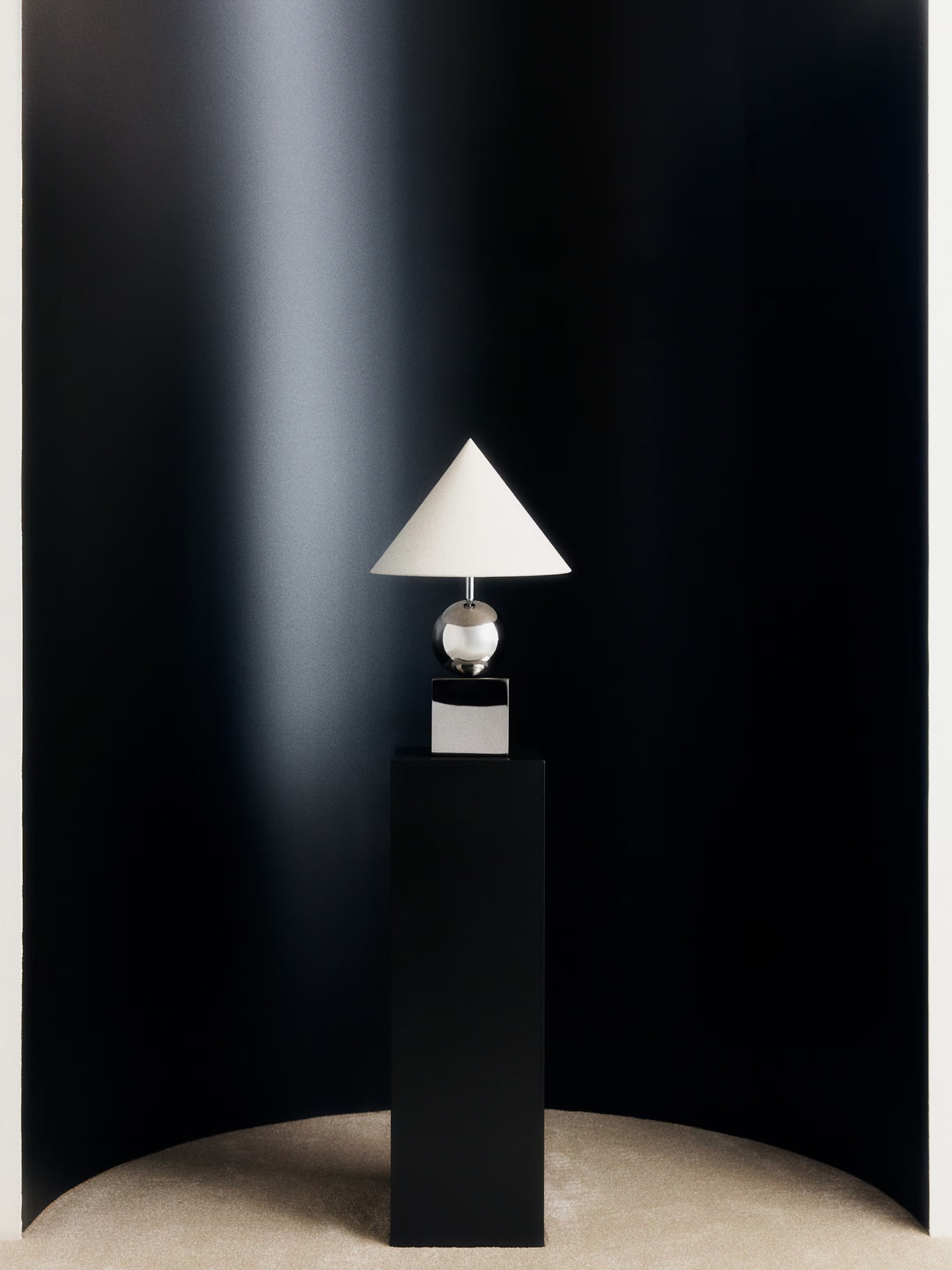H&M Home table lamp on a black pedestal against a dark backdrop