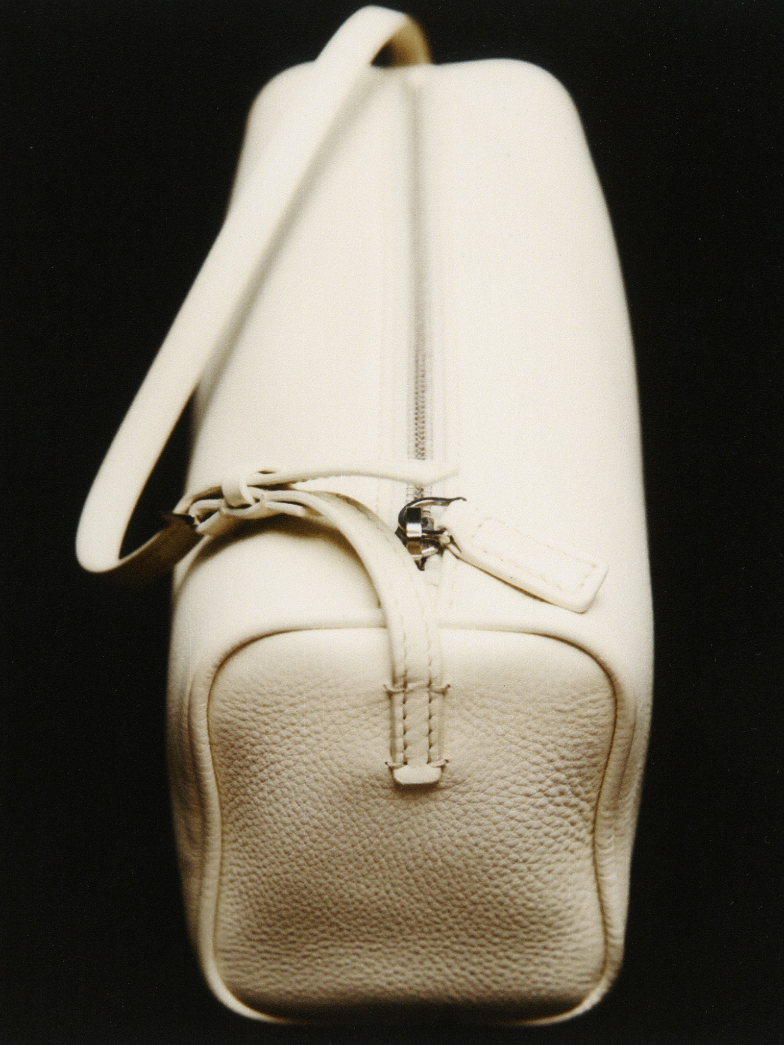 Cream leather Jil Sander bag photographed against a dark background