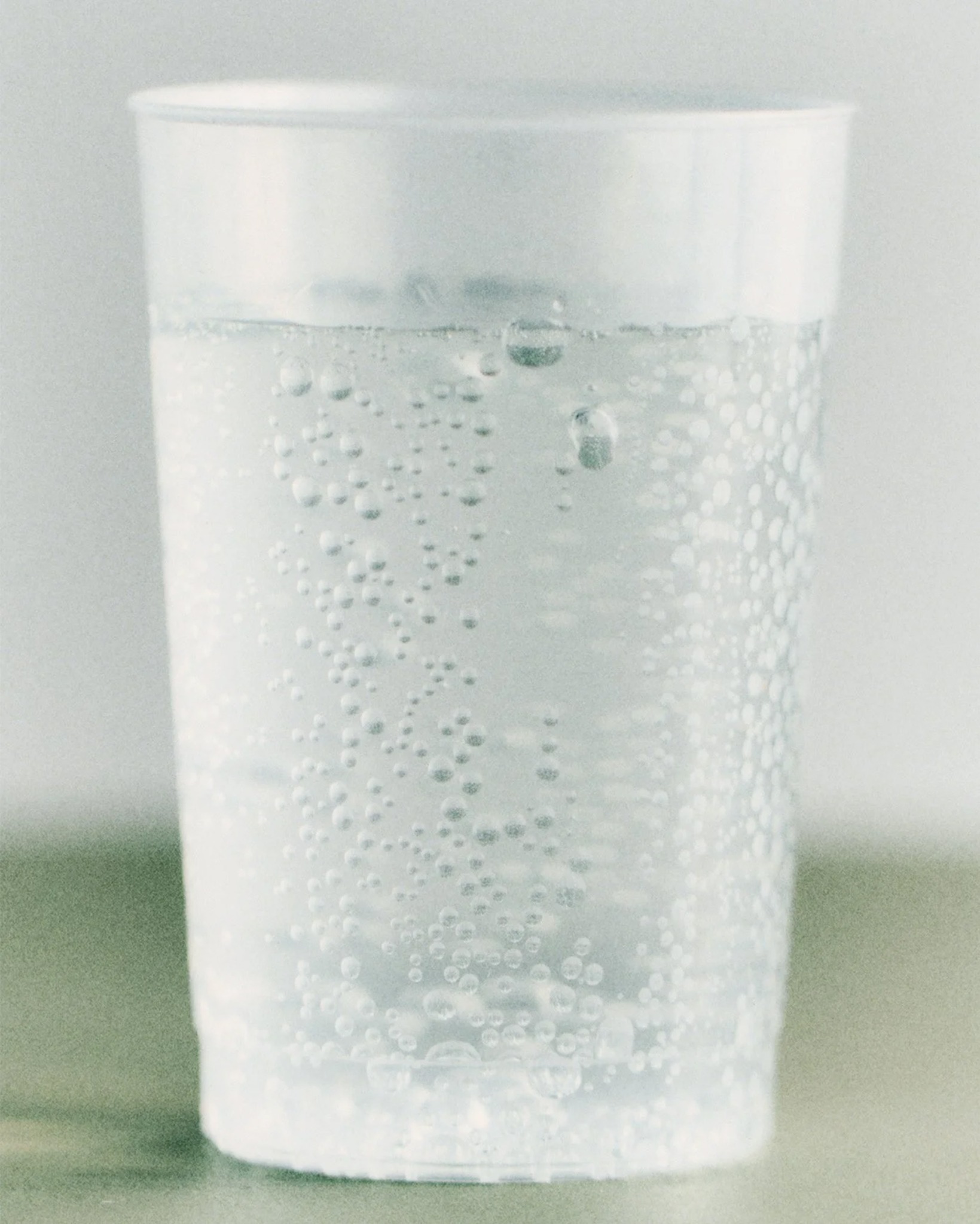 Close-up of a textured glass filled with water on a pale surface